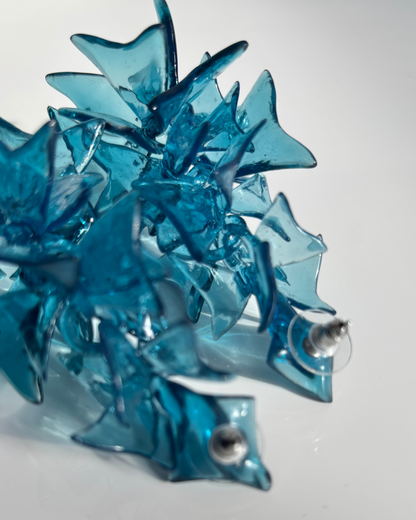 Close-up of large blue sculptural web earrings showing layered resin detail