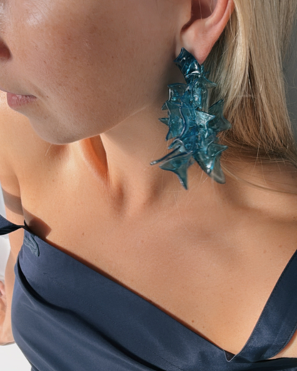 Model wearing blue earrings, profile focusing on the earring near the neck