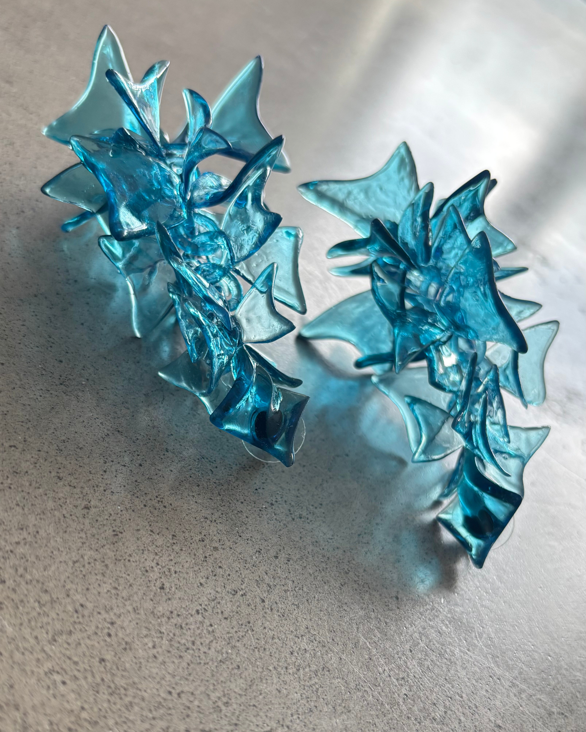 Pair of bright blue Gothic Drip Web earrings 3D printed resin on neutral background