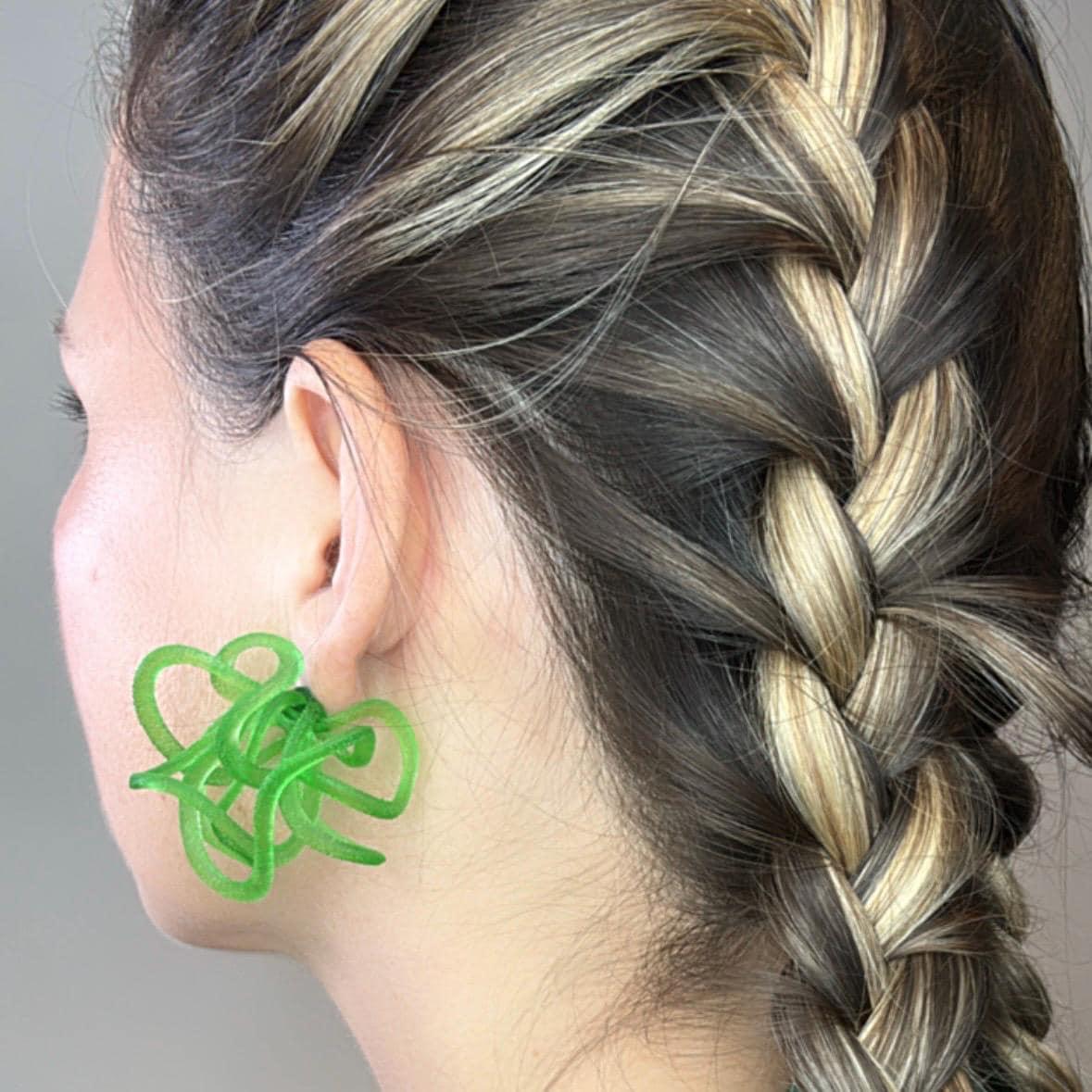 Close-up of emerald green fashion jewelry worn on the model's ear.