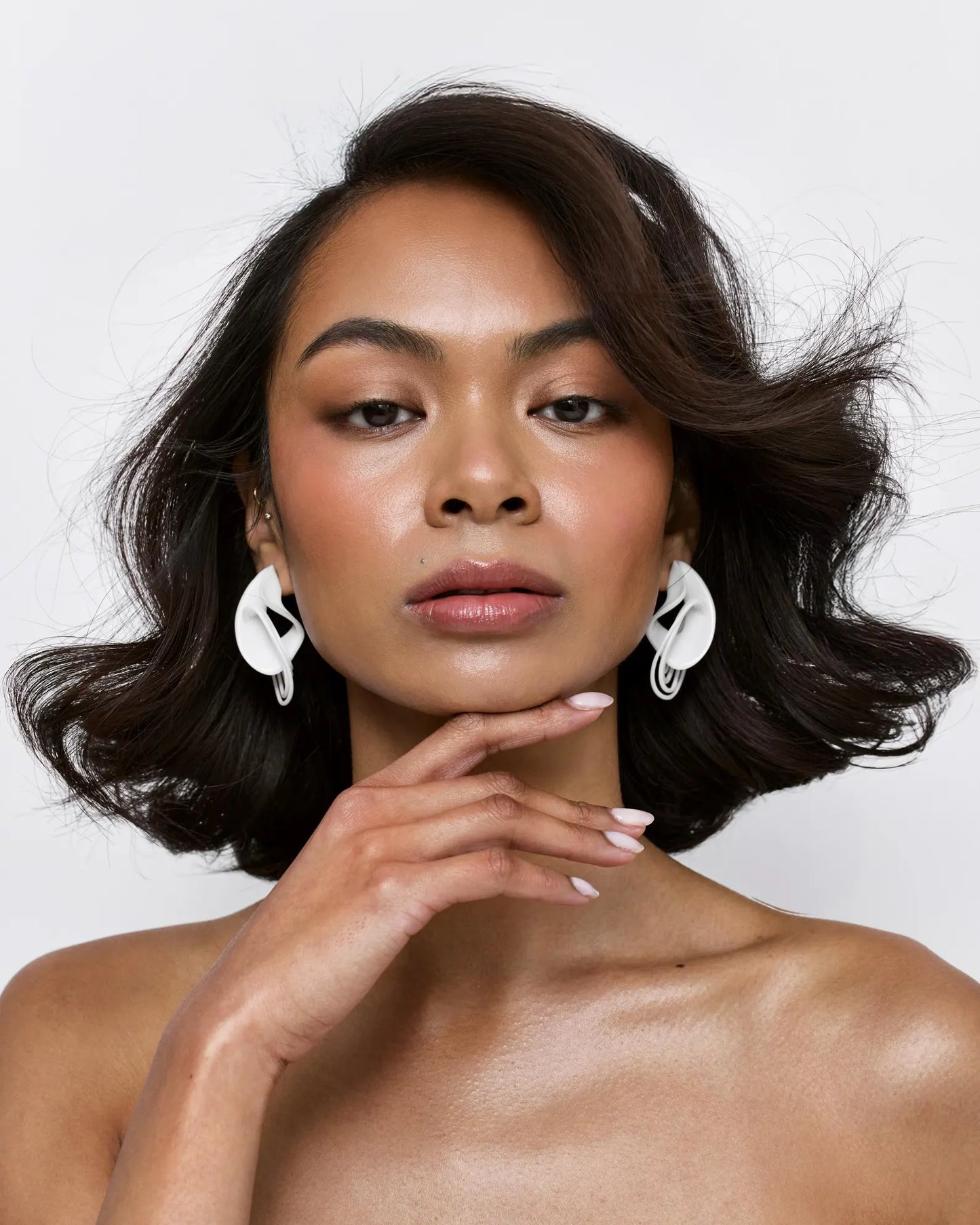 Woman with styled hair and earrings against a white background