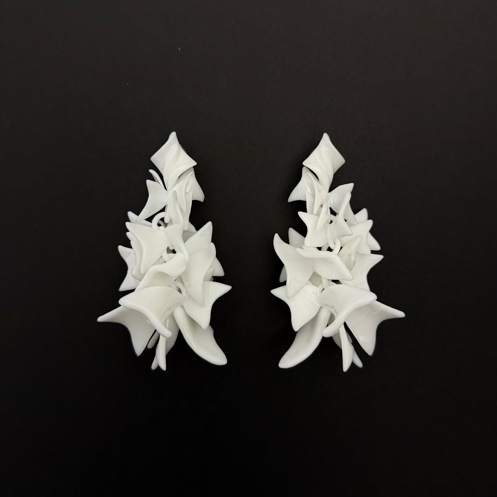 Pair of white petal cascade earrings on a black background