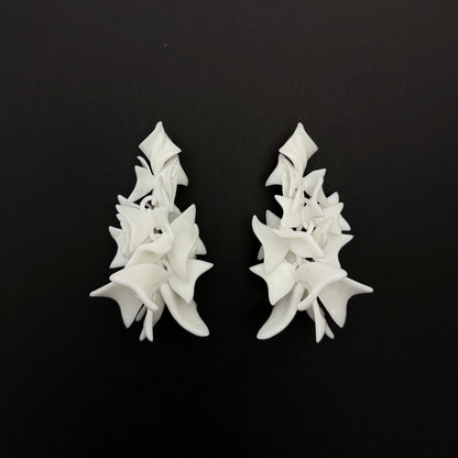 Pair of white petal cascade earrings on a black background