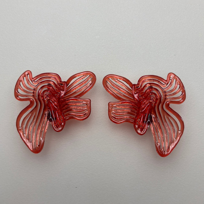 Two red butterfly-shaped 3d printed earring on a light gray background