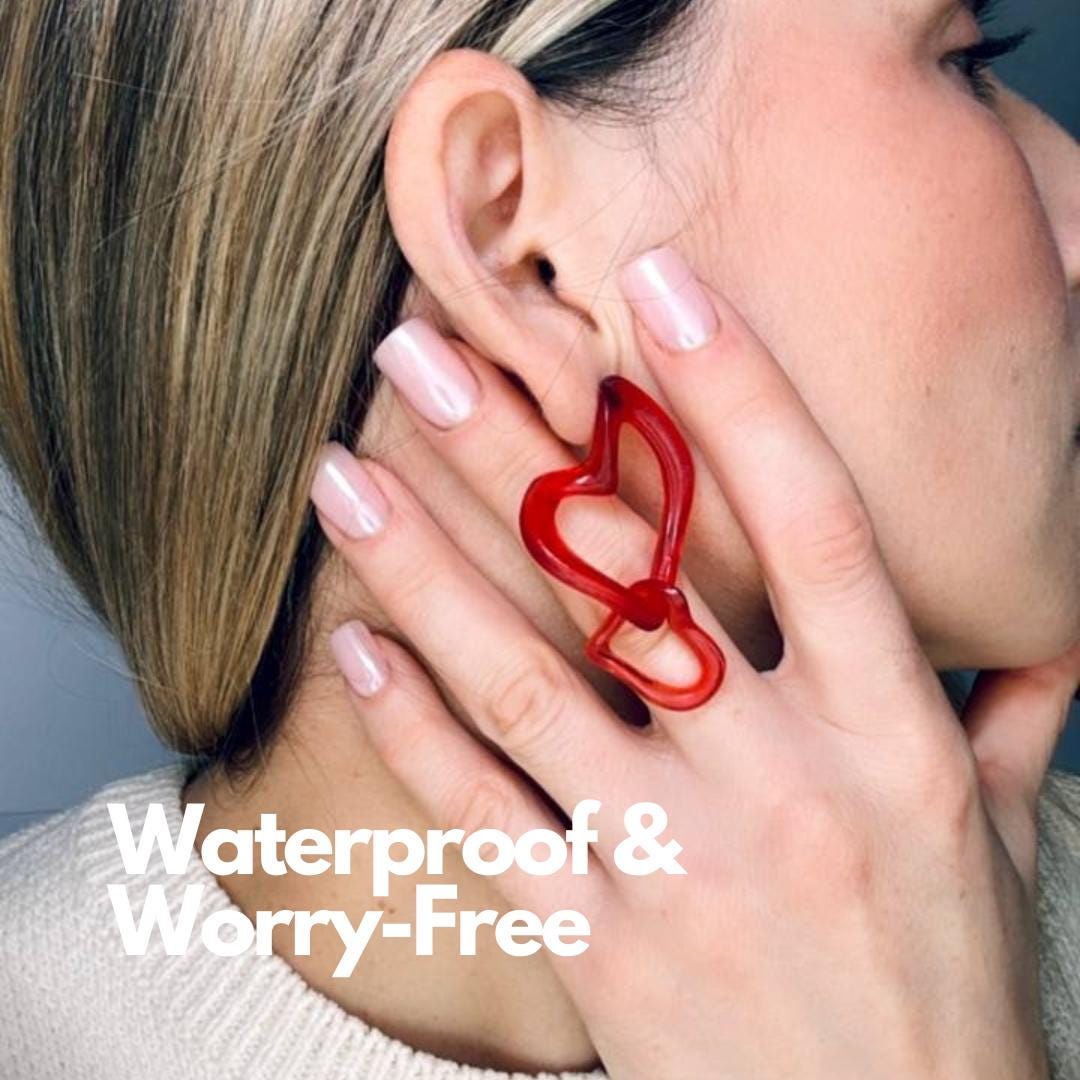 Red heart-shaped earring worn by a person.