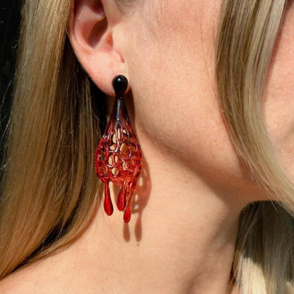 Model wearing red designer earrings, emphasizing the drop and profile.