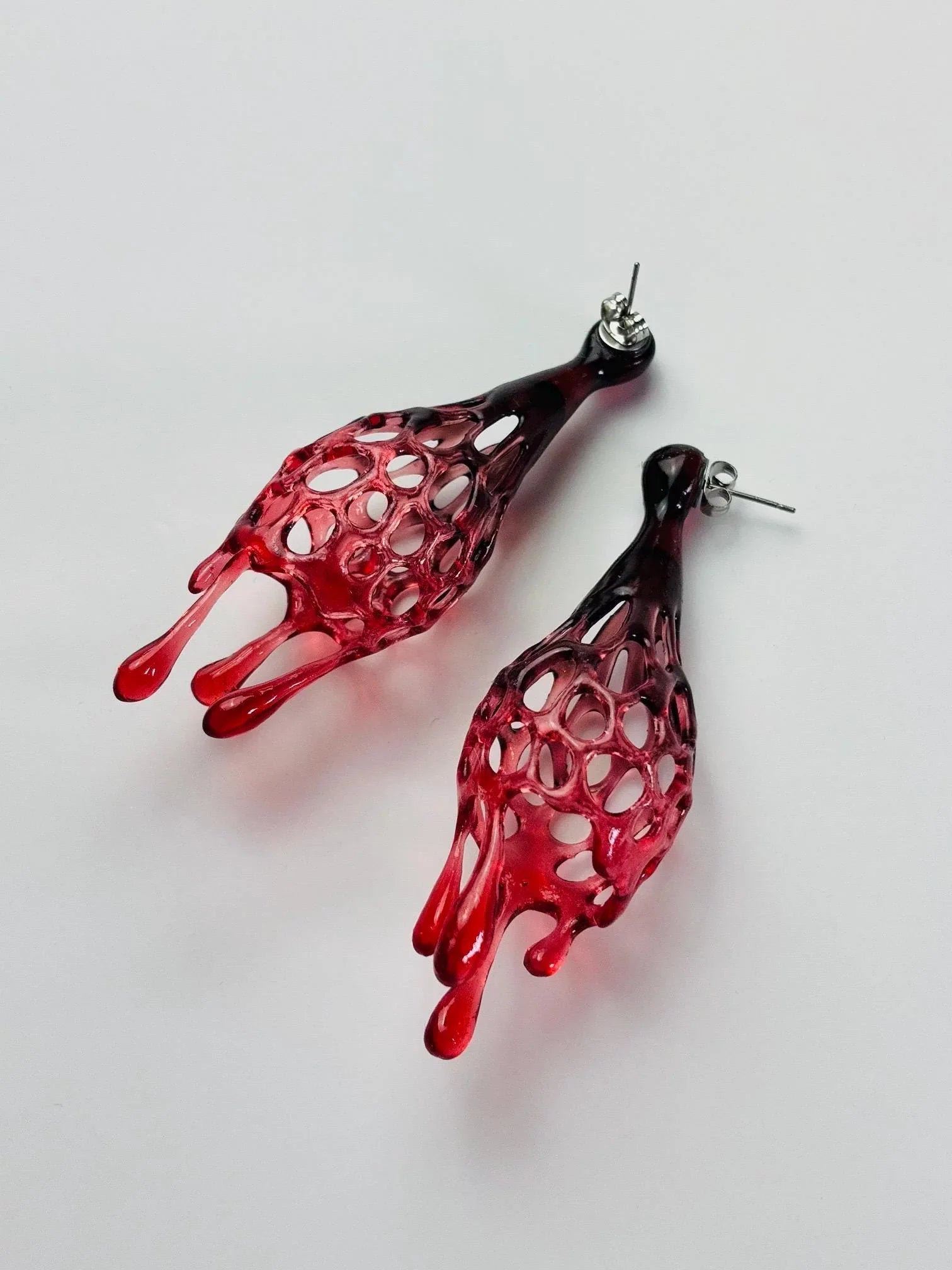 Side view of bold red avant garde jewelry displayed flat.