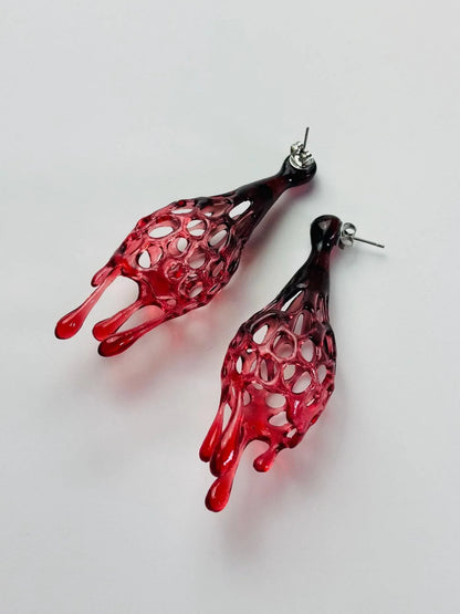 Side view of bold red avant garde jewelry displayed flat.