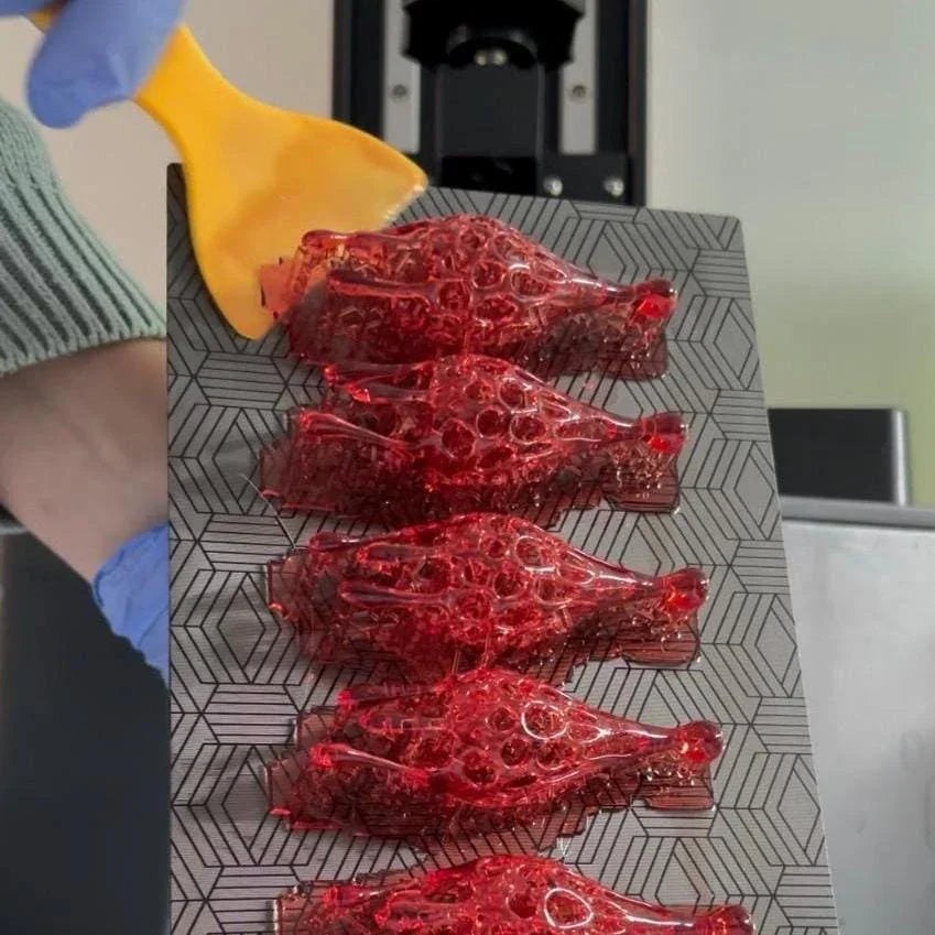 Raw 3d printed statement jewelry (red drip earrings) fresh off the printer, showing the initial creation process