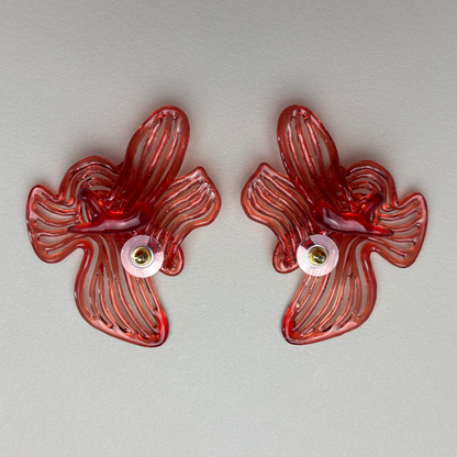 Pair of red flover shaped 3d printed earring on a light gray background