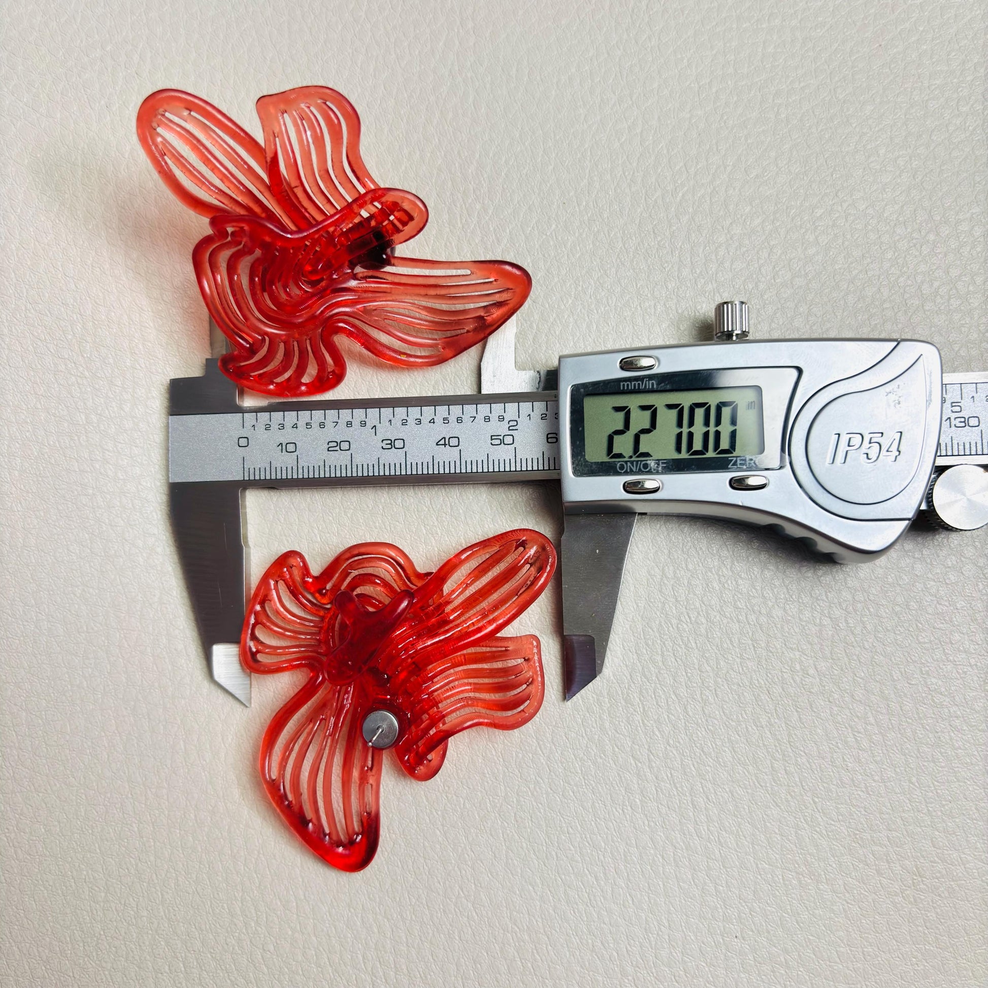 Pair of Cherry Red Rhythm earrings next to a measuring caliper to show size and scale
