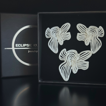 White sculptural floral earrings and ring set on black display box