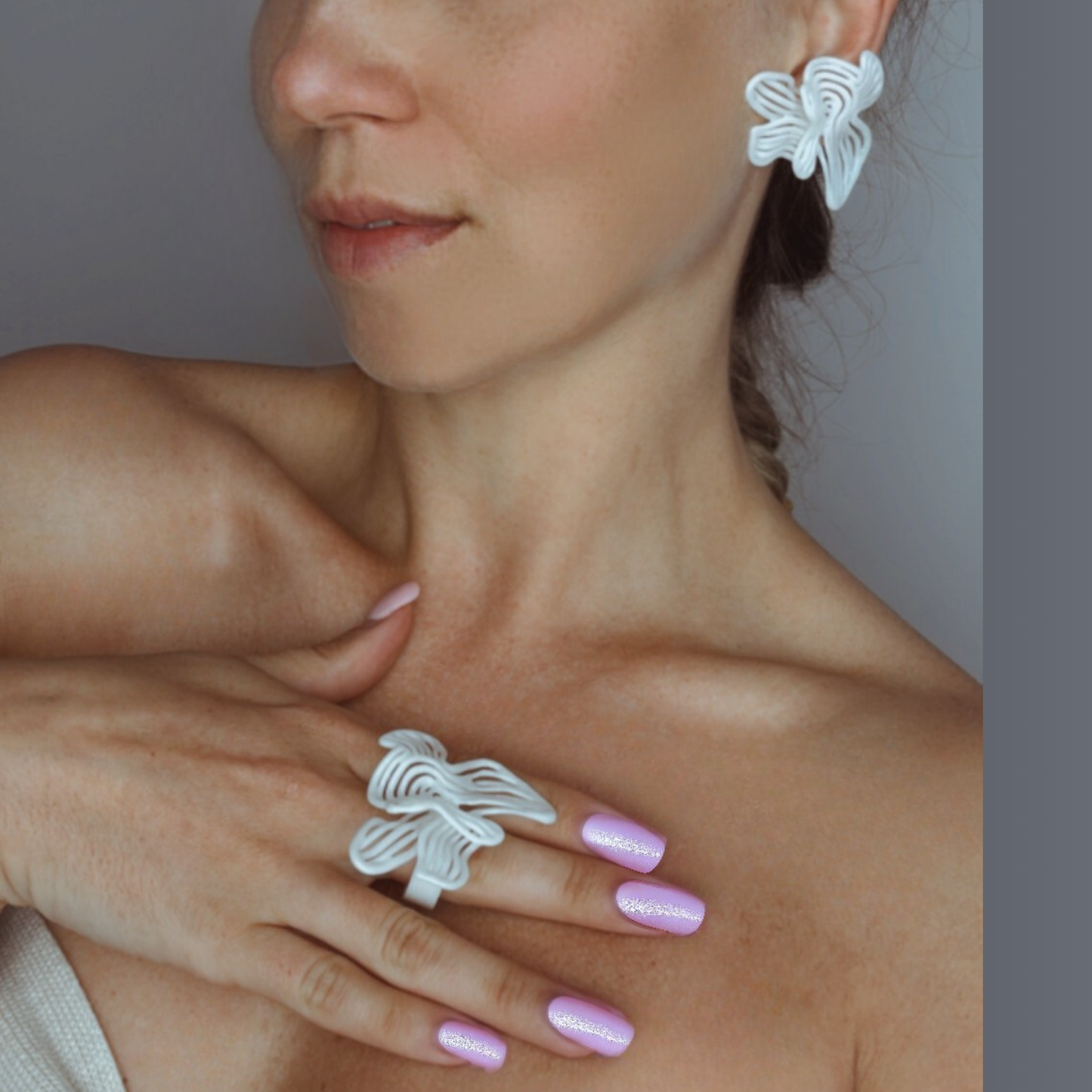 Model with hand on chest showing the statement Rhythm White earrings and ring