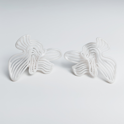 Two white butterfly-shaped earrings on a light gray background