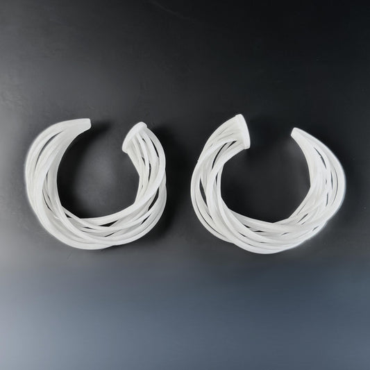 Pair of sculptural art jewelry hoops displayed flat.