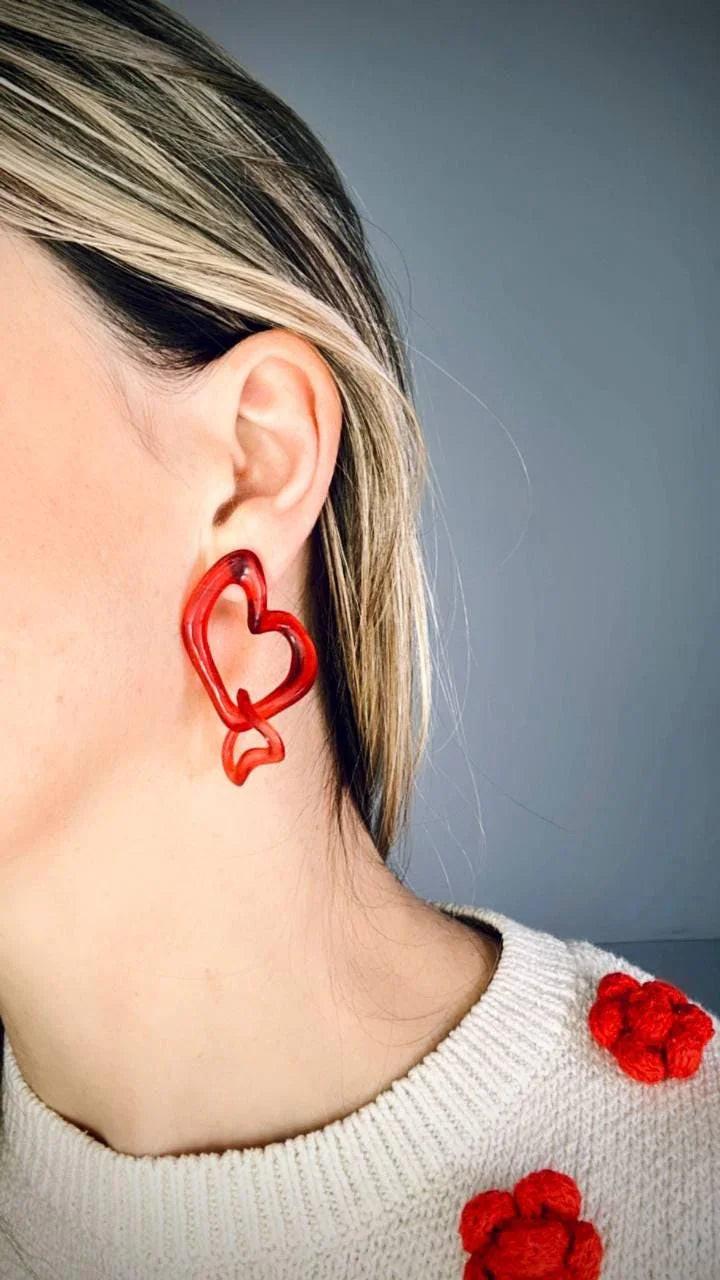 Angled view of model wearing red heart statement jewelry.