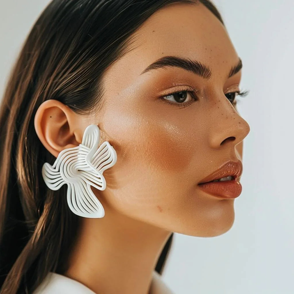 Close-up of white rhythm sculptural earrings on the model's ear, showing the detail.