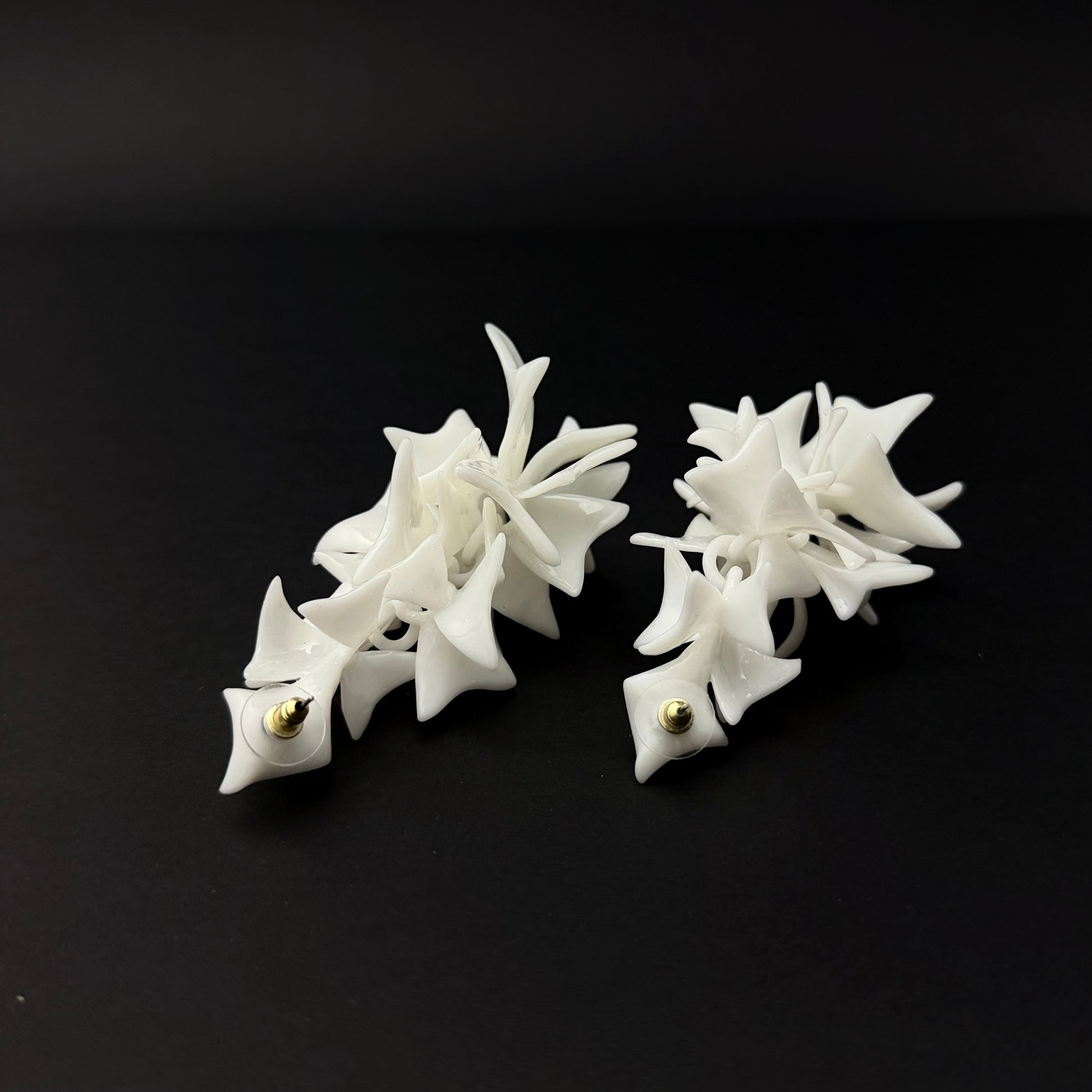 Pair of white star-shaped earrings on a black background