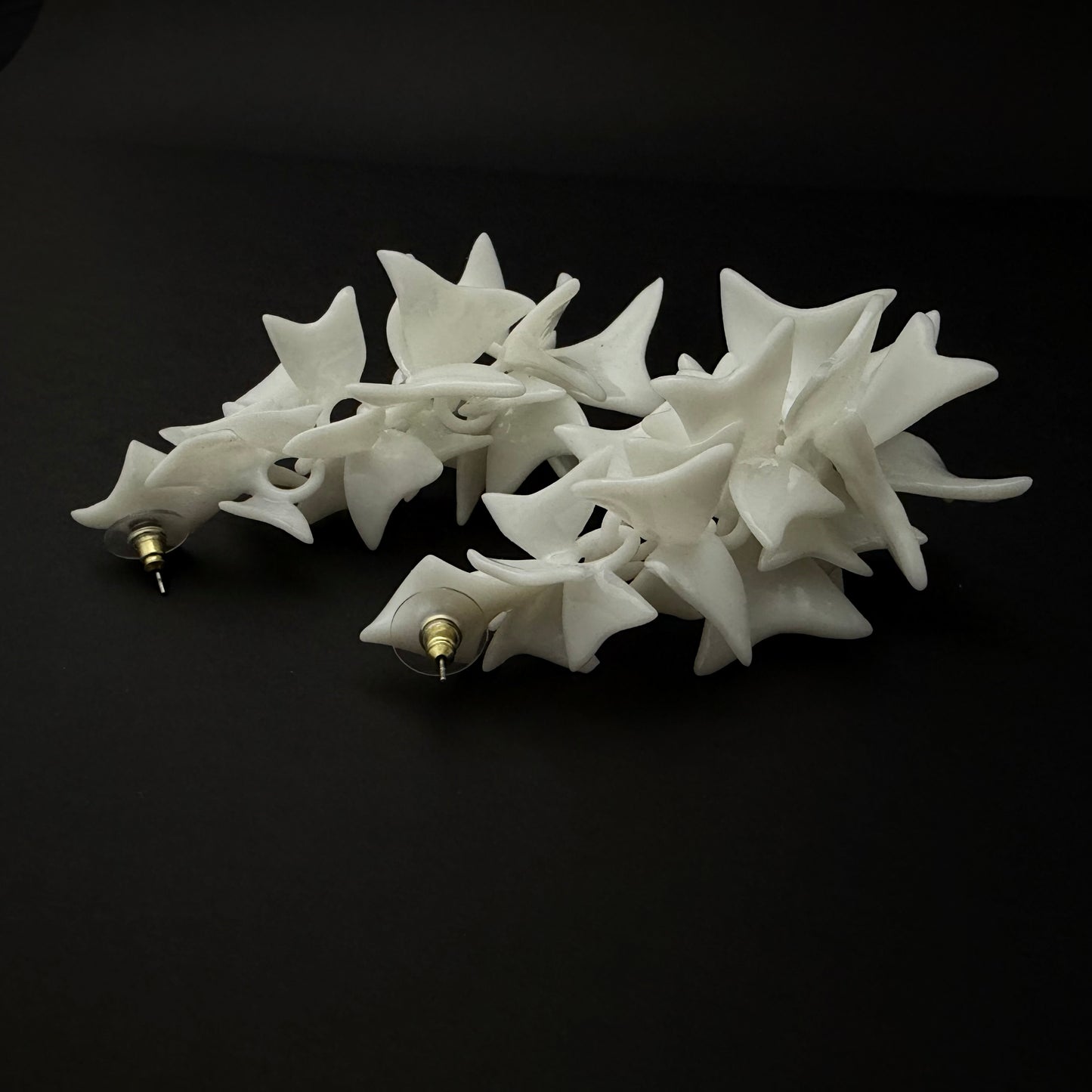 White star-shaped earrings hair clip on a black background