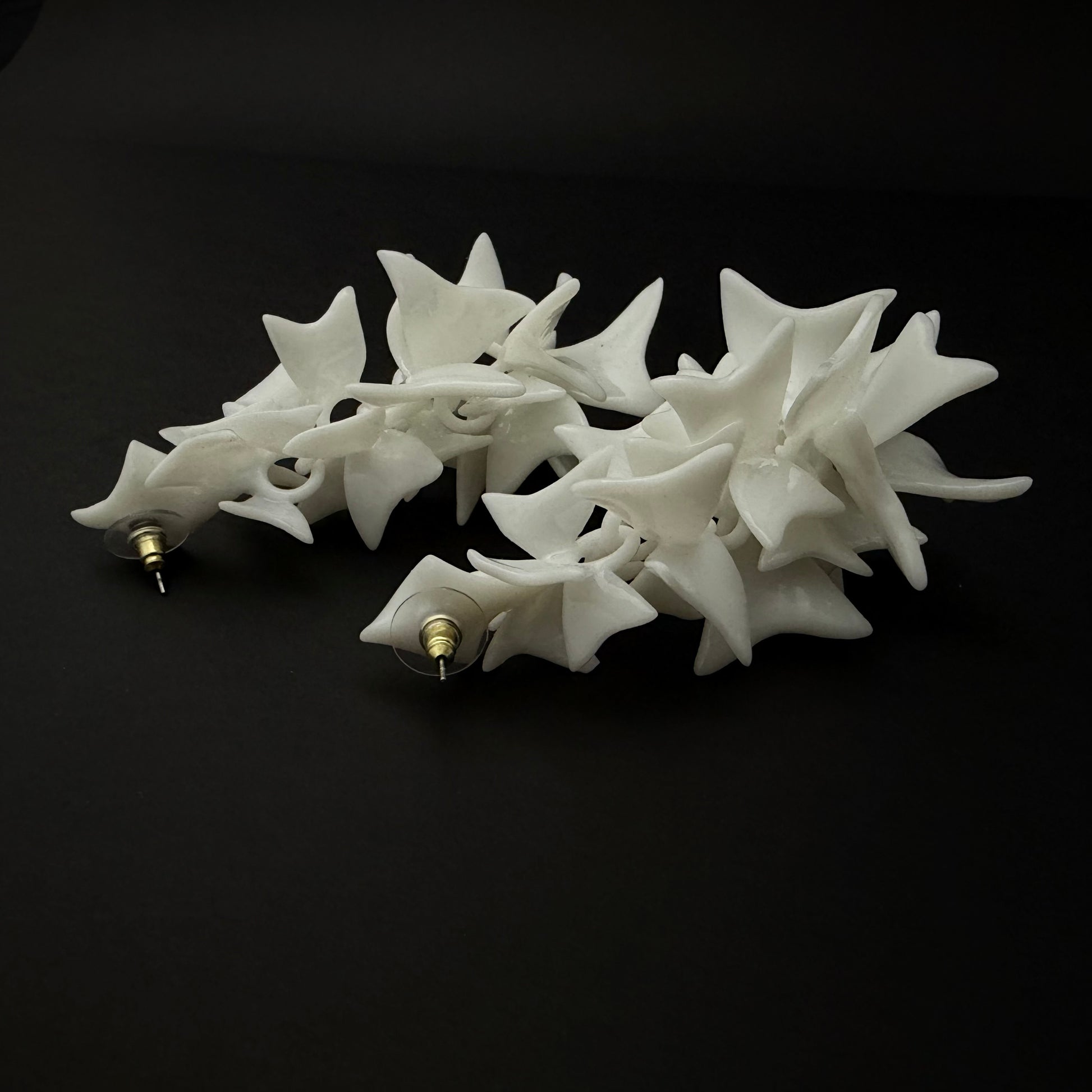 White star-shaped earrings hair clip on a black background